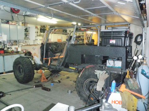 1961 International Scout 800 - A 1961 International Scout 800 is undergoing extensive modifications, including a custom roll cage and oversized tires, in a workshop setti…