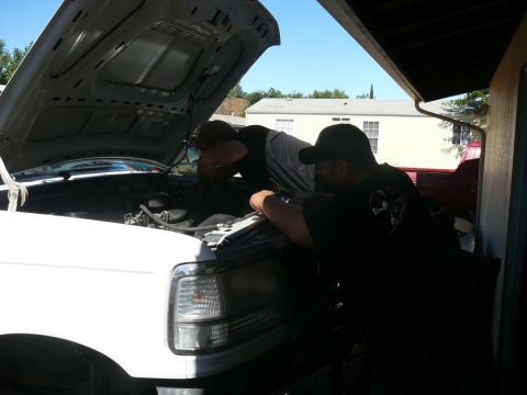 1988 Ford Bronco - Mechanics attend to the engine of a white truck, hood raised for access.