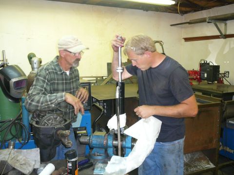 1988 Ford Bronco - Two men are focused on disassembling a car component in a workshop setting.