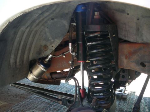 1988 Ford Bronco - Close-up view of the front suspension system, highlighting the coil spring and shock absorber assembly.