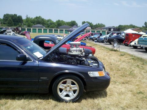 1999 Mercury Grand Marquis - A dark blue 1999 Mercury Grand Marquis is parked with its hood open at an outdoor car show.