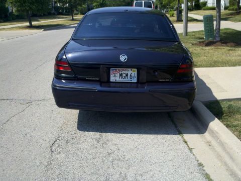 1999 Mercury Grand Marquis - The rear of a dark sedan is shown parked on a residential street.