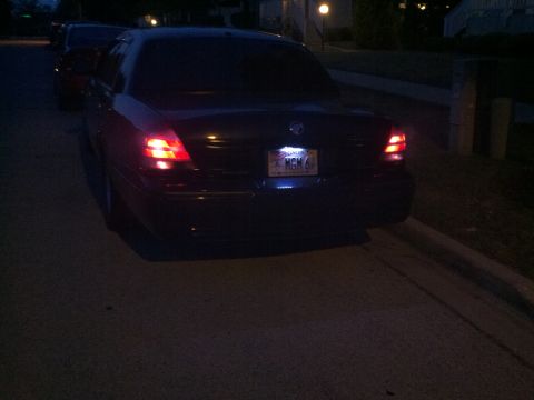 1999 Mercury Grand Marquis - Rear view of a dark sedan parked on a street at night, with its brake lights illuminated.