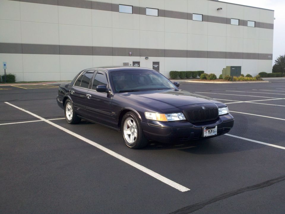 Dark blue Mercury Grand Marquis in empty lot, front three-quarter view