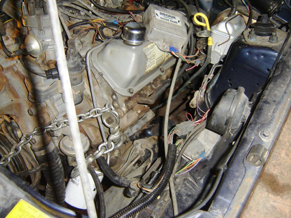 Engine bay with a chain attached to the engine block, showing various wires and components