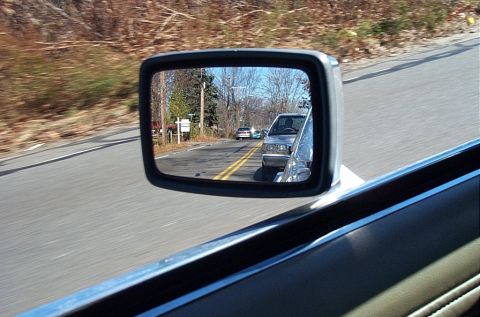 1991 Ford LTD Crown Victoria - A view through a side mirror shows multiple vehicles traveling on a road with double yellow lines.