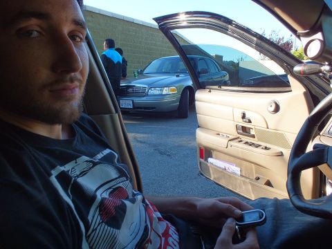 2003 Ford Crown Victoria - Driver holds a key fob in a tan-interior car as a silver Ford sedan sits beyond the open door.