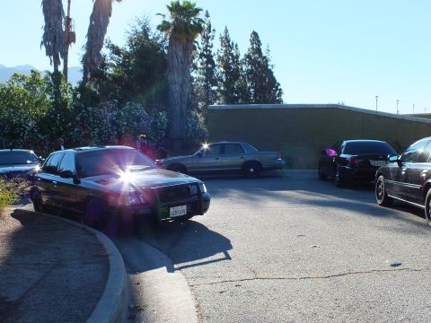 2003 Ford Crown Victoria - Lowered black Panther-platform sedan with three more cars beyond on a sunlit parking loop