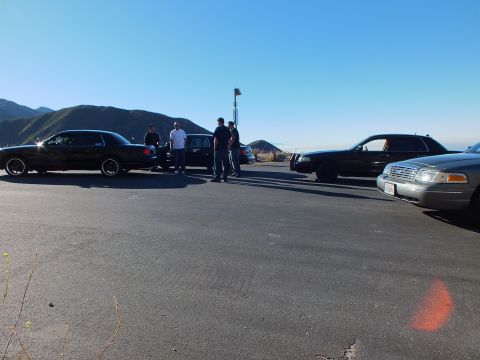 2003 Ford Crown Victoria - Lowered black sedans face a silver Crown Victoria nose-on at a mountain pull-out