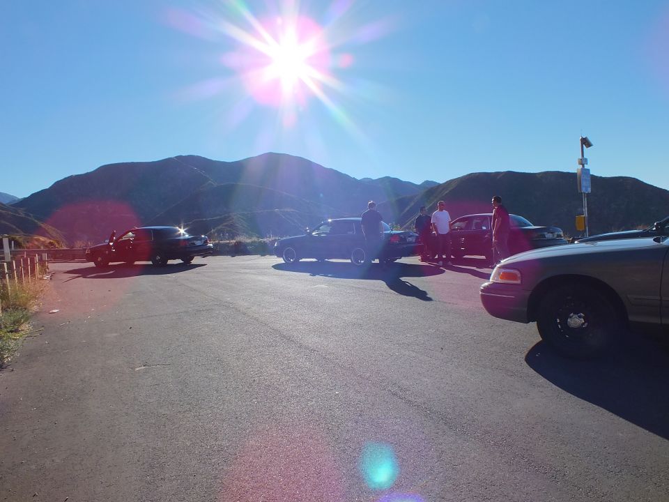 Cars parked at mountain overlook with strong sun flare over the ridge