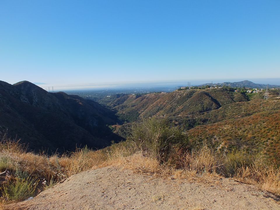 Scenic canyon overlook with hazy valley and brushy hills under blue sky