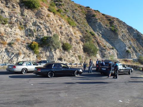 2003 Ford Crown Victoria - Lowered Panther sedans and a silver sedan gathered at a cliffside pull-out