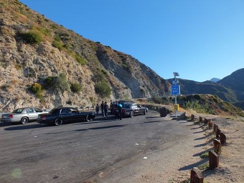 2003 Ford Crown Victoria - Several sedans and people at a paved canyon overlook with wooden guardrail posts