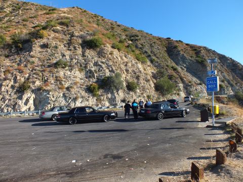 2003 Ford Crown Victoria - Lowered Panther sedans and bystanders at a paved overlook under a tan ridge