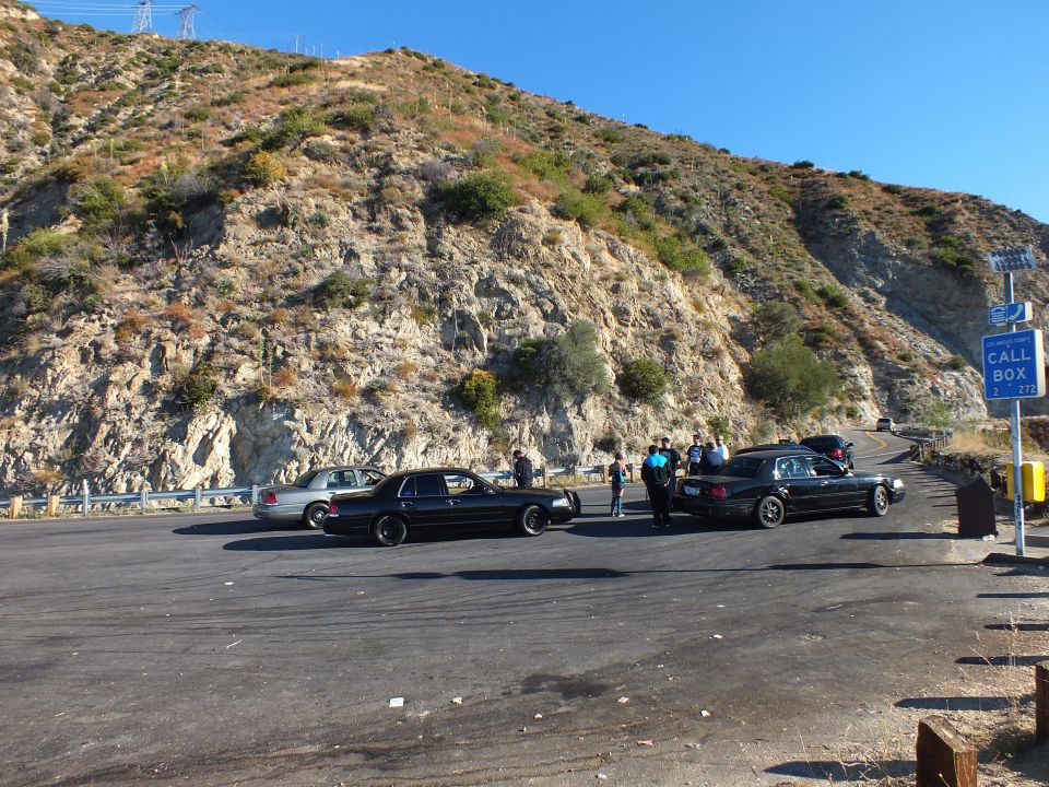 Black full-size sedans and people at hillside pull-out with Call Box sign