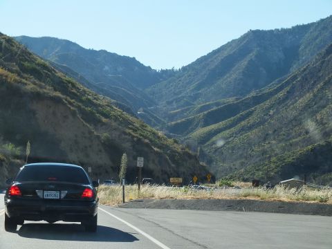 2003 Ford Crown Victoria - Black full-size Ford sedan slowing on a mountain road near yellow warning signs