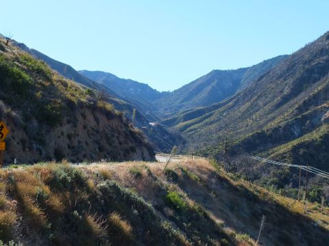 2003 Ford Crown Victoria - View down a dry chaparral canyon with a road cut and transmission lines in afternoon light.