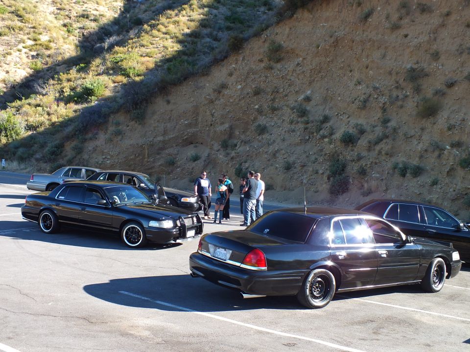 Black Ford Crown Victoria and Mercury Grand Marquis sedans parked at hillside lot