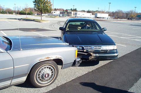 1991 Ford LTD Crown Victoria - A black 1992 Ford Crown Victoria has front-end damage after being hit by a silver car in a parking lot.
