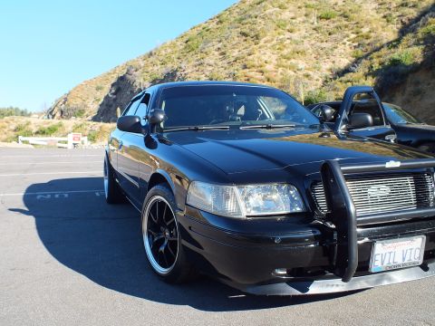 2003 Ford Crown Victoria - Dark sedan with brush guard displays a personalized California plate reading EVIL VIC.
