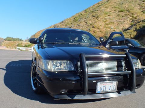 2003 Ford Crown Victoria - Front of a lowered black sedan with brush guard and EVIL VIC California license plate.