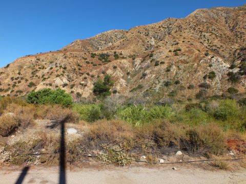 2003 Ford Crown Victoria - Eroded chaparral mountainside rises above a sandy wash dotted with shrubs and rocks.