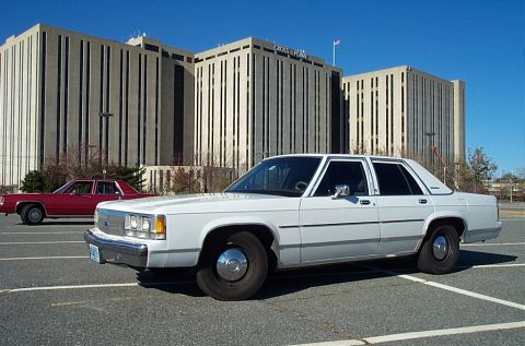 1991 Ford LTD Crown Victoria - A white Ford Crown Victoria sedan is parked in a lot with another car in the background.