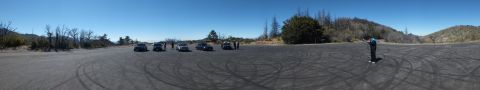 2003 Ford Crown Victoria - Panoramic view of cars parked on a skid-marked lot ringed by dry brush.