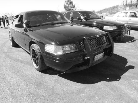 2003 Ford Crown Victoria - Monochrome shot of a blacked-out full-size sedan with push bumper on a lot