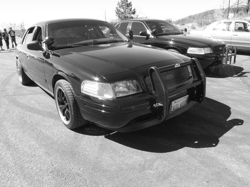 Black-and-white photo of a black Grand Marquis with brush guard and EVIL VIC plate