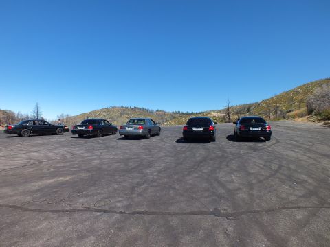 2003 Ford Crown Victoria - Full-size sedans staged tail-out on a tire-marked pad below blue sky and hills