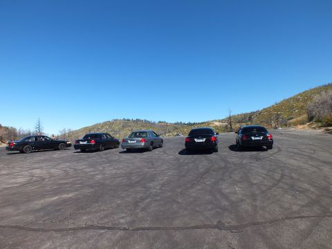 2003 Ford Crown Victoria - Lineup of five sedans seen from rear on a mountaintop paved area beside dry hills