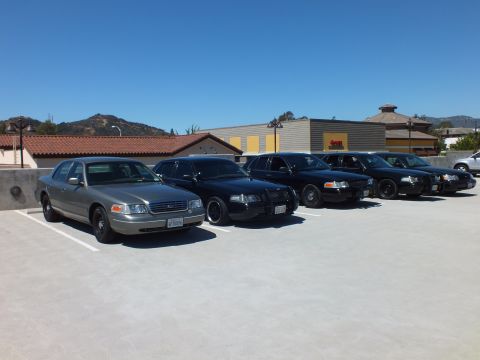 2003 Ford Crown Victoria - Front three-quarter view of silver and black Crown Victoria sedans lined up on a deck