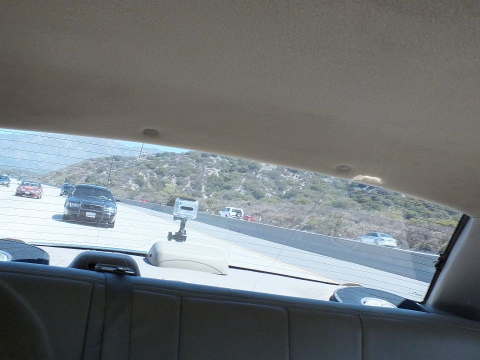 Highway and hills seen through a car rear side window with phone mount on parcel shelf