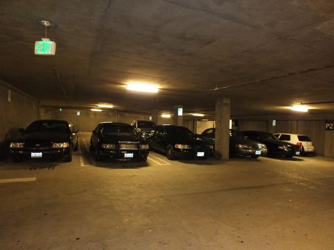 2003 Ford Crown Victoria - Dark Crown Victoria sedans on a P2 garage level lit by overhead fluorescents.
