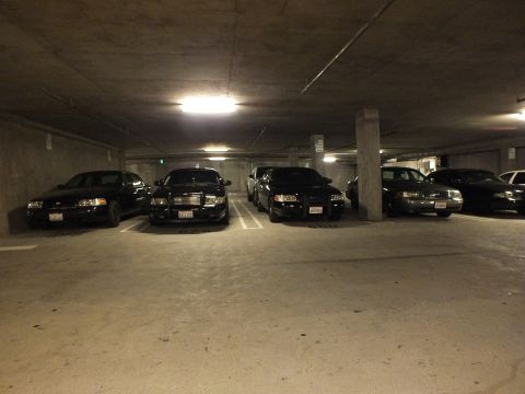 2003 Ford Crown Victoria - Dark Crown Victoria sedans parked nose-out under garage lighting.
