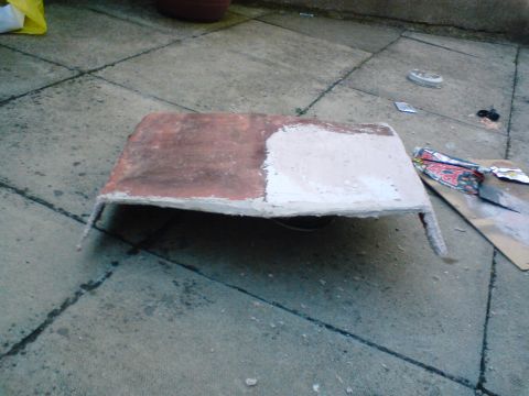 1989 Ford Bronco - A rectangular object, half covered in red primer and half in white primer, rests on a concrete surface.