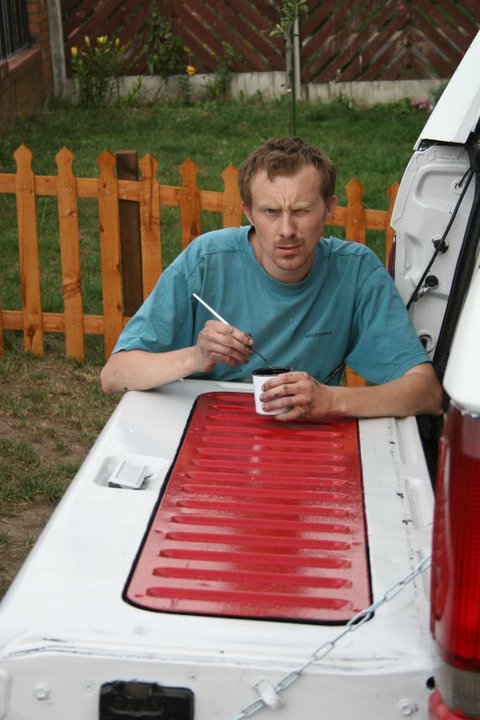 1989 Ford Bronco - A man is painting red stripes onto the tailgate of a white vehicle.