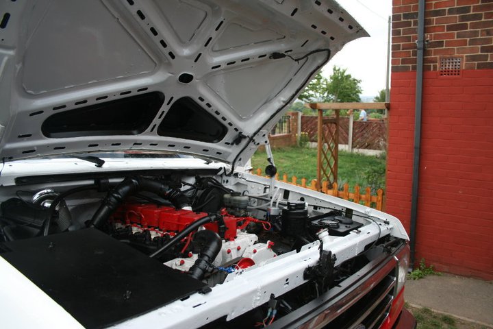 White truck engine bay with red engine block and "SUPERMOTORS" logo