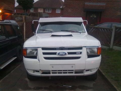1989 Ford Bronco - A white Ford pickup truck is parked in a driveway, showing damage to its front bumper.