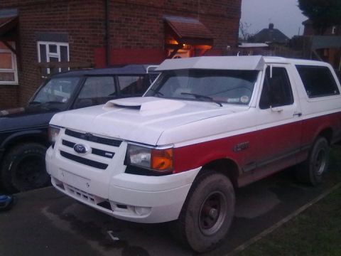 1989 Ford Bronco - A two-tone white and red Ford Bronco is parked next to another vehicle.