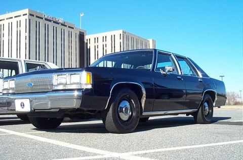 1991 Ford LTD Crown Victoria - Dark 1991 Ford Crown Victoria LTD sedan parked in a lot with buildings in the background.