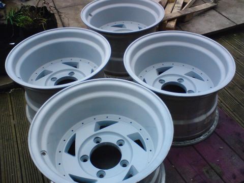 1989 Ford Bronco - Four aluminum alloy wheels are shown, possibly prepped for painting or refinishing.