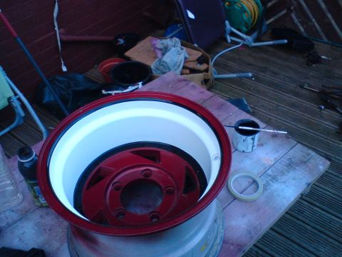 1989 Ford Bronco - A car wheel is being prepped for painting, with supplies laid out on a deck.
