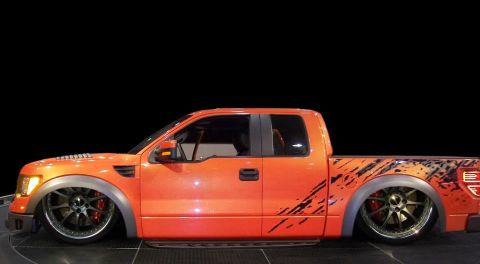 2007 Ford Mustang - Custom orange pickup truck with graphics and lowered suspension sits on display.