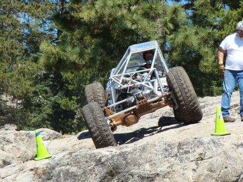 1989 Ford Bronco - A custom-built buggy with a prominent roll cage is shown traversing a challenging rocky obstacle course.