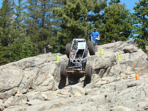 1989 Ford Bronco - A custom-built off-road buggy navigates a challenging rocky terrain during an event, with spectators watching.