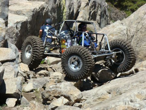 1989 Ford Bronco - A custom-built buggy with a roll cage and large tires is shown crawling over large rocks.