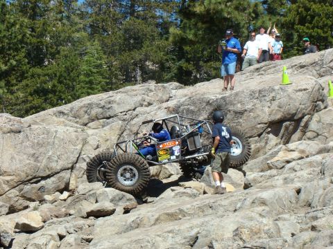 1989 Ford Bronco - A custom-built off-road buggy navigates a challenging rocky course with spectators watching from above.