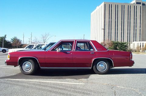 1991 Ford LTD Crown Victoria - Side view of a red 1991 Ford Crown Victoria LTD sedan in a parking lot.